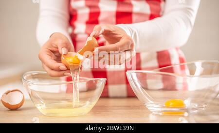 Detail of woman's hands separating egg yolks from the whites into two glass bowls Stock Photo