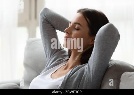 Woman puts hands behind head enjoy relaxation meditation at home Stock Photo