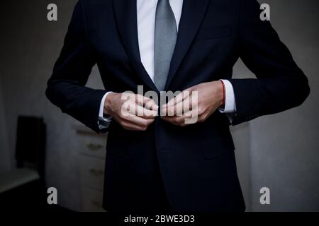man puts on suit in the room Stock Photo