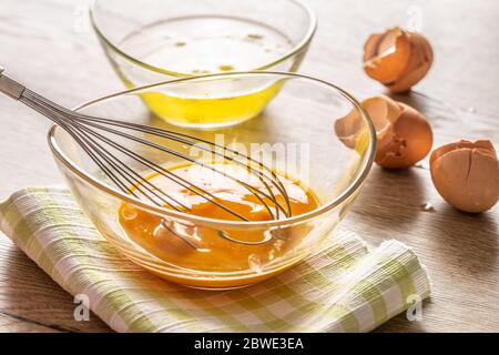 Whisked egg yolks in a glass bowl with egg whites in a second bowl and crackjed egg shells on the side Stock Photo