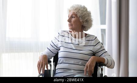 Sad depressed elderly woman sitting in wheelchair at home Stock Photo
