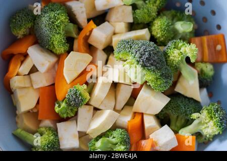 Cut and raw vegetables in strainer, broccoli, carrots Stock Photo