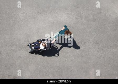 Woman with a baby stroller standing on a city street. Concept of motherhood, road safety, single mom with pram Stock Photo