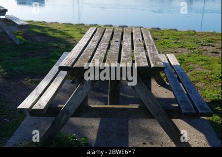 A great place for a picnic, a wooden table with bench seats sits in front of the sea Stock Photo