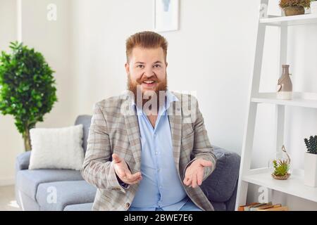 Online looking at camera. A bearded smiling man looking at the camera video web chat call online welcomes waving his hand at home. Stock Photo