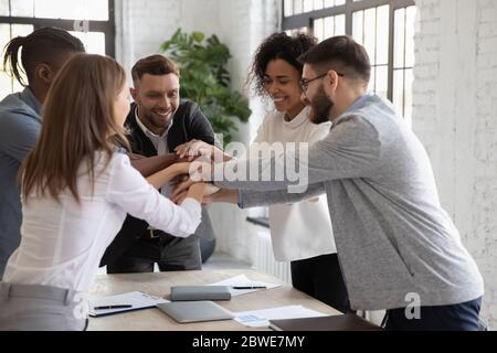 Successful diverse employees stacking hands, engaged in team building Stock Photo