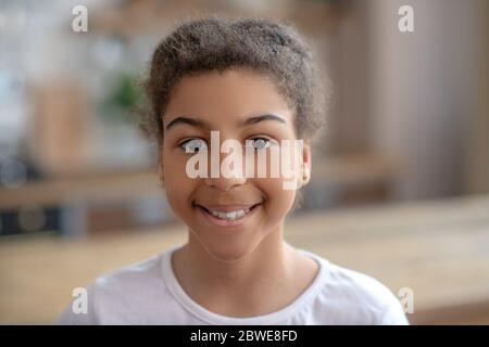 Cute curly-haired girl smiling and looking pleased Stock Photo