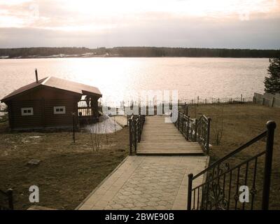 Wooden house on the river. Sunset, spring. House on the river with sunset view. Evening sunrise on a choppy river wind early spring landscape. Sunset Stock Photo