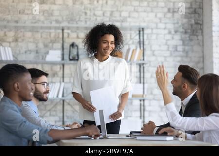 Employee raising hand, asking question to African American business coach Stock Photo