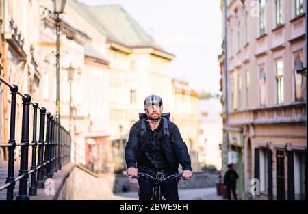 Front view of delivery man courier with bicycle cycling in town. Stock Photo