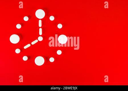 Clock made of white tablets on red background, top view Stock Photo