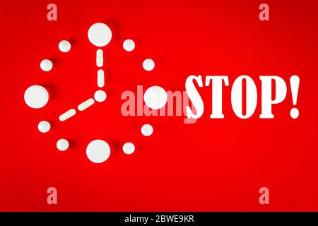 Clock made of white tablets with inscription STOP , on red background, top view. 2019 Novel Coronavirus 2019-nCoV concept. Stock Photo