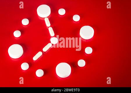 Clock made of white tablets on red background, top view Stock Photo