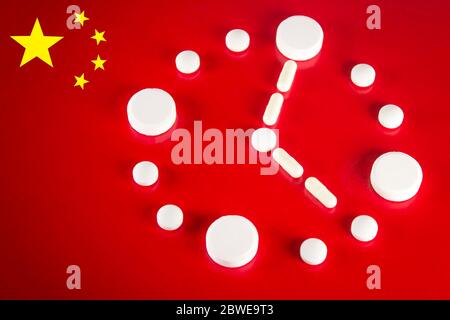 Clock made of white tablets on red background of the Chinese flag, top view. 2019 Novel Coronavirus 2019-nCoV concept Stock Photo
