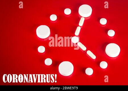 Clock made of white tablets with inscription CORONAVIRUS on red background, top view. 2019 Novel Coronavirus 2019-nCoV concept. Stock Photo