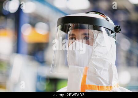 Close-up portrait of worker with protective mask and suit in industrial factory. Stock Photo