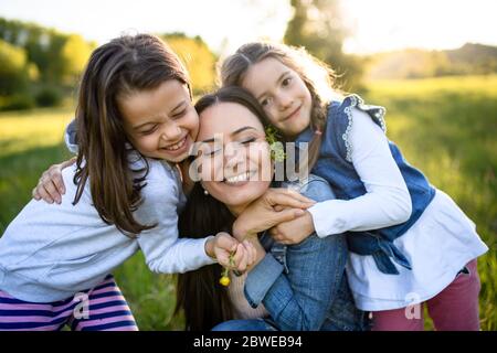 Mother with two small daughters having fun outdoors in spring nature, hugging. Stock Photo