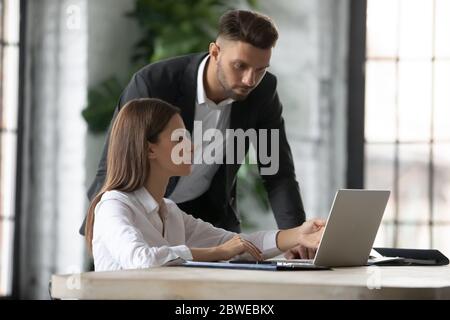 Businesswoman intern asking questions about project to serious confident mentor Stock Photo