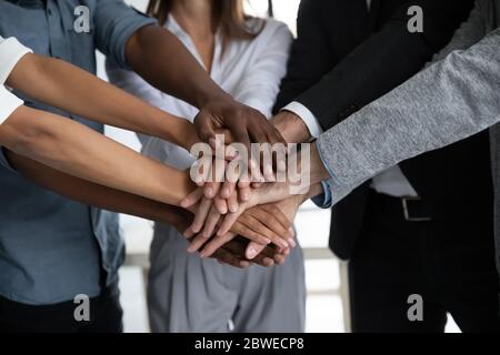 Close up diverse colleagues stacking hands, showing unity and support Stock Photo