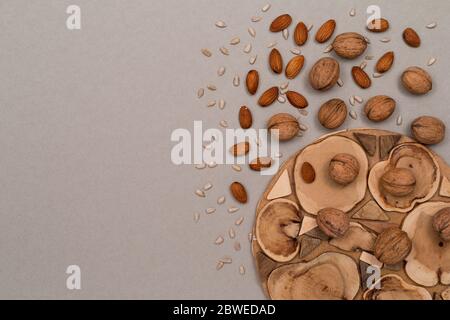 Nuts, inshell walnuts, peeled almonds, peeled sunflower seeds, sprinkled on a table, kraft paper and wooden background. Top view with copyspace, flat Stock Photo