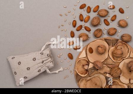 Nuts, inshell walnuts, peeled almonds, peeled sunflower seeds, sprinkled on a linen bag, kraft paper and wooden background. Top view with copyspace Stock Photo