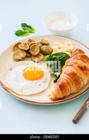 Healthy breakfast, fried eggs with spinach pancake cereals cheese and croissant in a plate. Overjead view. Stock Photo