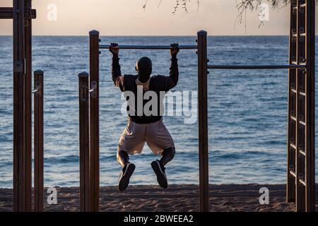Afro man doing pull ups on horizontal bar at the beach. Sport And Lifestyle. Stock Photo