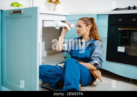 Female plumber fixing problem with drain pipe Stock Photo