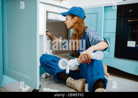 Female plumber fixing problem with drain pipe Stock Photo