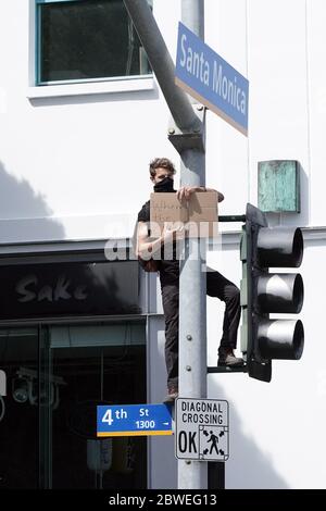 Santa Monica, United States. 31st May, 2020. CALIFORNIA, USA. MAY 30 2020: A man on a traffic signal at 4th Street and Santa Monica Blvd. with a sign that reads 'Where's the change?' during a protest over the death of George Floyd, Saturday, May 30, 2020, in Santa Monica, Calif. Protests were held in U.S. cities over the death of Floyd, a black man who died after being restrained by Minneapolis police officers on May 25. (Photo by IOS/Espa-Images) Credit: European Sports Photo Agency/Alamy Live News Stock Photo