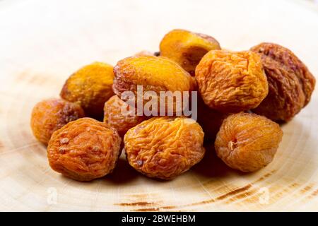 Dried apricot with a bone closeup on a wooden table. Baking ingredients. Healthly food. Stock Photo