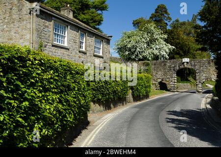 Country lane, cottage, stone archway (historic aqueduct, 3 arches, headroom warning sign 10' 9'') - B6160 Bolton Abbey village, Yorkshire, England, UK Stock Photo