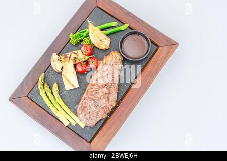 Closeup of rare roasted juicy medallion of fillet. Gourmet beef steak with vegetables and sauce, luxury stone wooden plate, luxurious dining Stock Photo