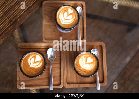 Two Cups of hot cappuccino on the plate with spoons on white wooden table background. Place for text. Top view. Stock Photo