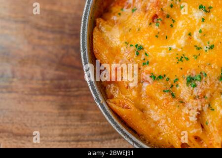 Baked pasta on wooden plate, basil with penne. Italian food background Stock Photo