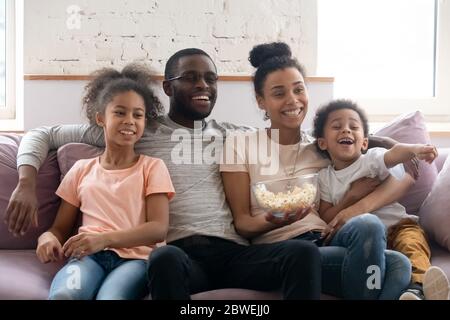 Full African family with kids watching TV sitting on couch Stock Photo