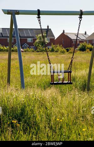 Long grass in a closed childrens' playground after 10 weeks of the coronavirus lockdown, Ashbourne, Derbyshire, June 2020 Stock Photo