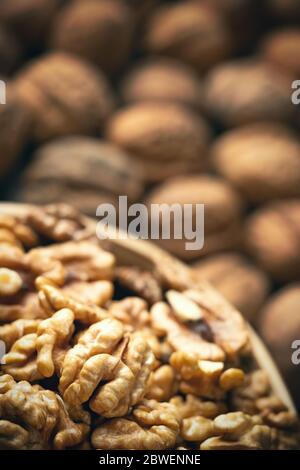 Fresh walnut kernels  in a bowl and blurred whole walnuts in background. Healthy organic food, BIO viands, natural background. Copy space for your adv Stock Photo