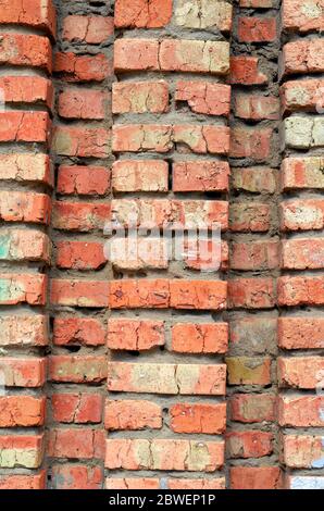 Red brick wall with ledges and cavities background. Old cracked clay brick wall. Basis For solving various design problems. Stock Photo