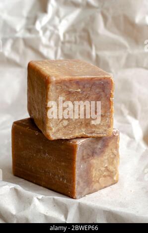 Two pieces of laundry soap on a plain background. Rectangular pieces of new soap. Natural hygiene products. Place for text. Selective focus. Stock Photo