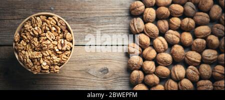 Fresh walnut kernels and whole walnuts in a bowl on rustic old wooden table. Healthy organic food, BIO viands, natural background. Copy space for your Stock Photo