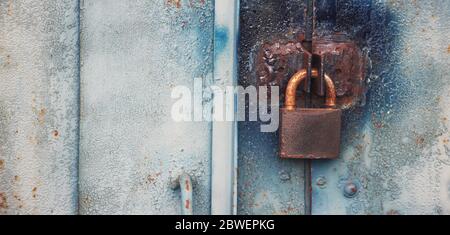 retro iron lock hanging on the garage door. a locked metallic door with padlock. Copyspace on the left. Security concept Stock Photo