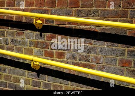 Bright Yellow Handrails Fixed To A Red Brick Wall Stock Photo