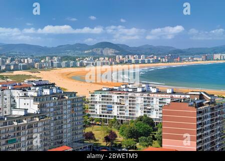 View of town with wide sand beach and green mountains in the background Stock Photo