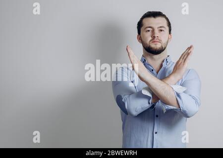 Man on a gray background. Shows hands stop. Stop racism. Stop virus.  Stock Photo