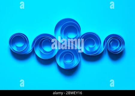 Abstract composition made from paper spirals on blue background