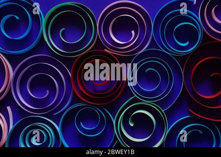 Multicolored spirals made from paper on blue background Stock Photo