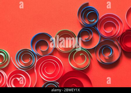 Multicolored spirals made from paper on red background Stock Photo