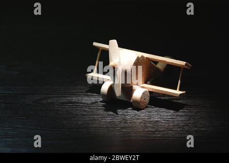 Travel concept. Small wooden airplane under beam of light on dark background Stock Photo