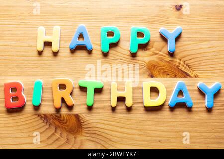 Happy Birthday words written with colorful letters on wooden background, top view Stock Photo